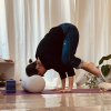 Yogapose Krähe mit dem Kopf auf einem dicken Bolster aufgestützt
